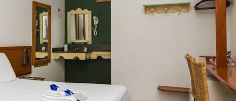 Una habitación de hotel con una cama, una silla, un escritorio, un espejo y un teléfono.