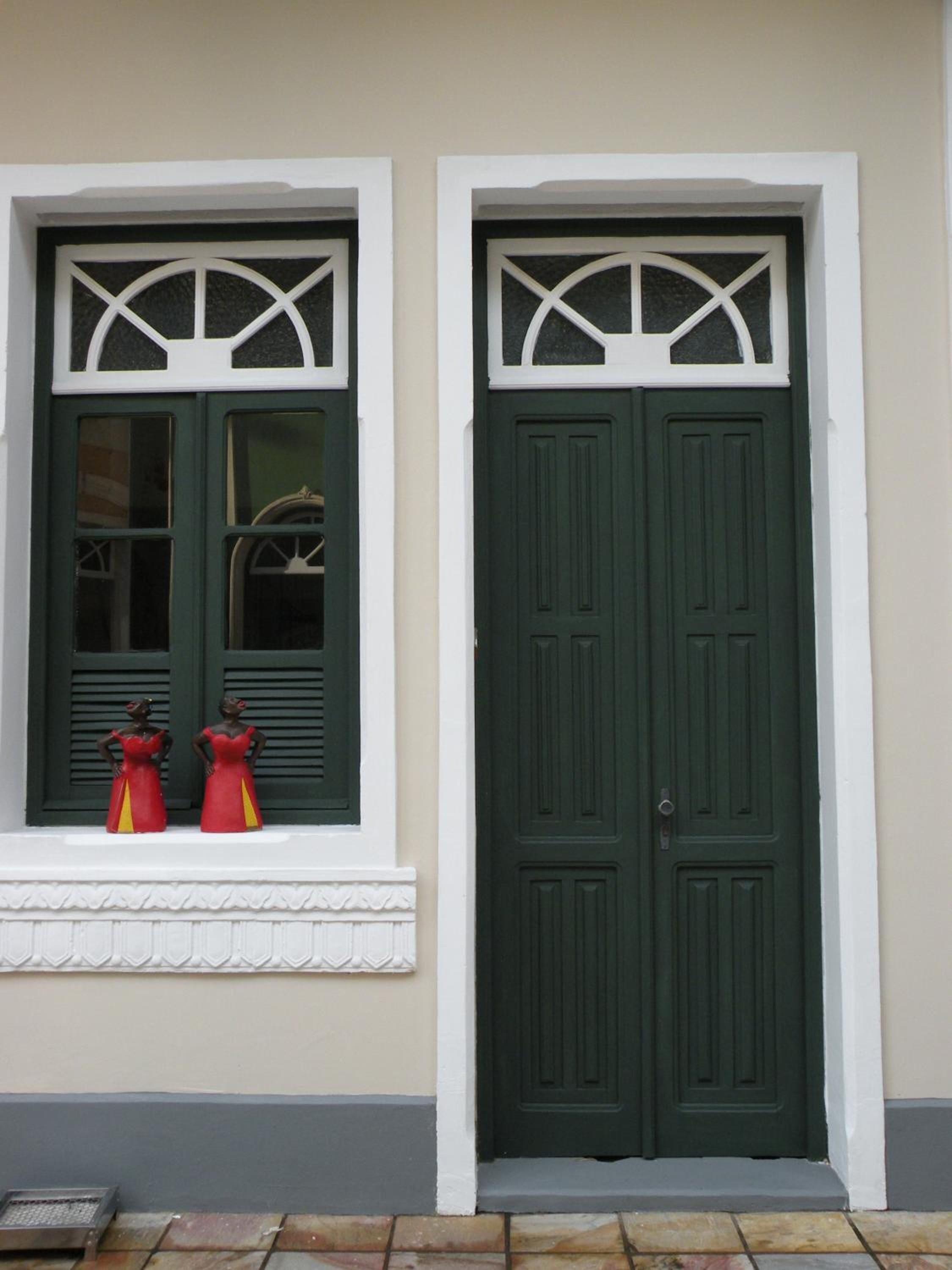 Un edificio con dos puertas verdes y ventanas con detalles blancos.