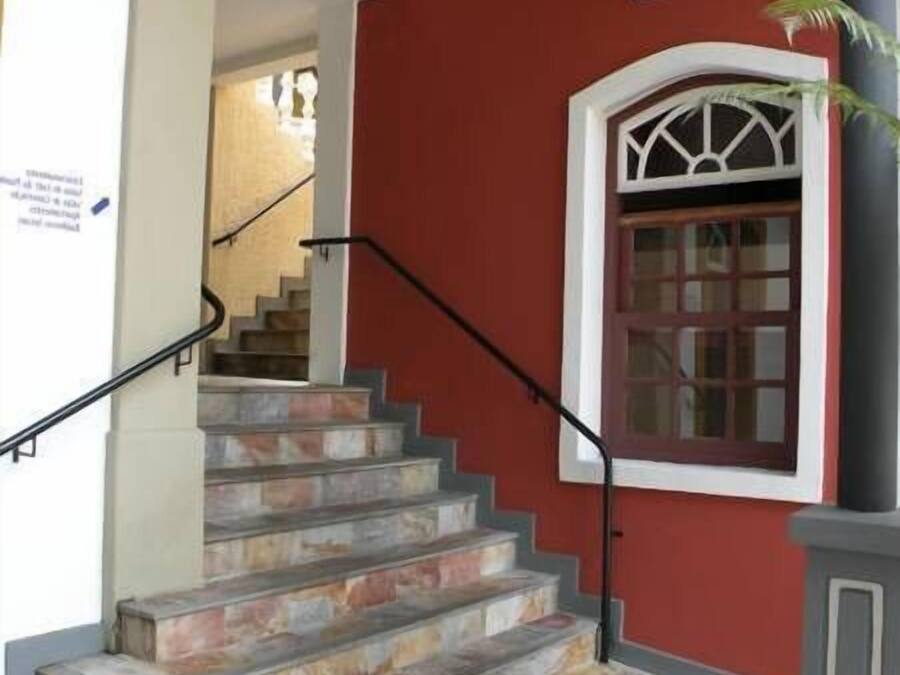 Eine Treppe führt zu einem roten Gebäude mit einem Fenster und einer Tür.