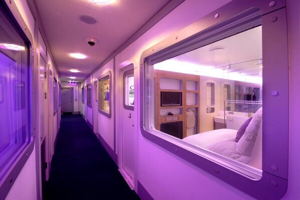 Ein Zugwagen mit privaten Schlafabteilen, jeweils mit einem Bett, einem kleinen Tisch und einem Fernseher.