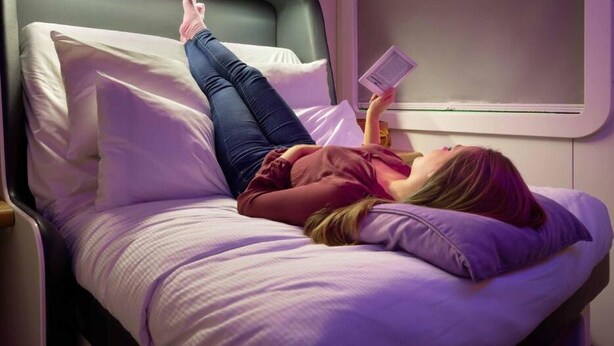 Eine Person liegt in einem Zimmer mit einem Bett, einem Fenster und einem Nachttisch.