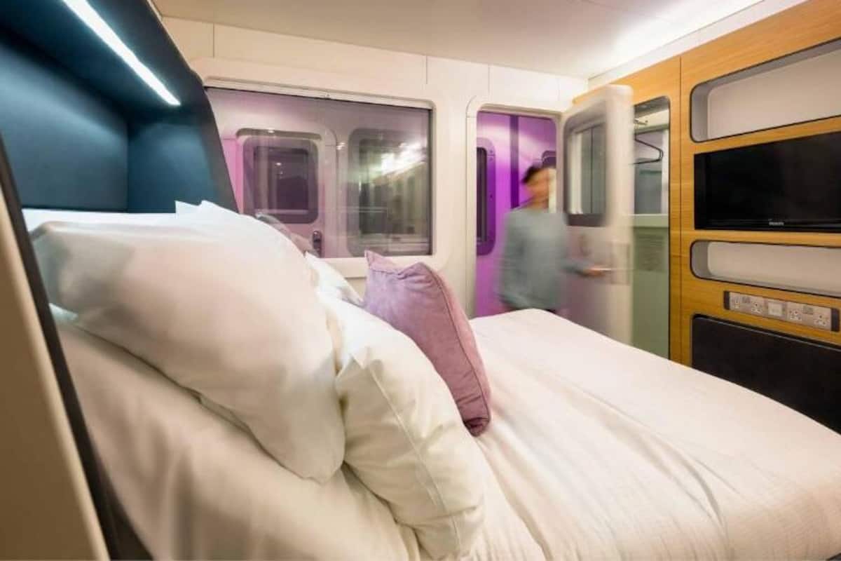 Ein Zugabteil mit einem Bett, einem Fernseher und einer Holzvertäfelung mit Bildschirm.