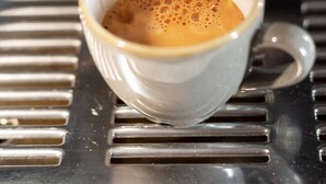 Kaffee wird aus einer Maschine in eine Tasse gegossen.