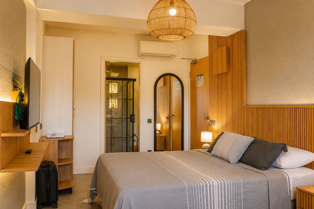 A hotel room with a bed, a TV, a shower, and a wooden panel wall.