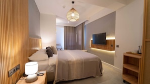 A modern hotel room with a neatly made bed, a bedside lamp, a flat-screen TV mounted on the wall, and a wooden nightstand. - Hotel Club-E (Fethiye)