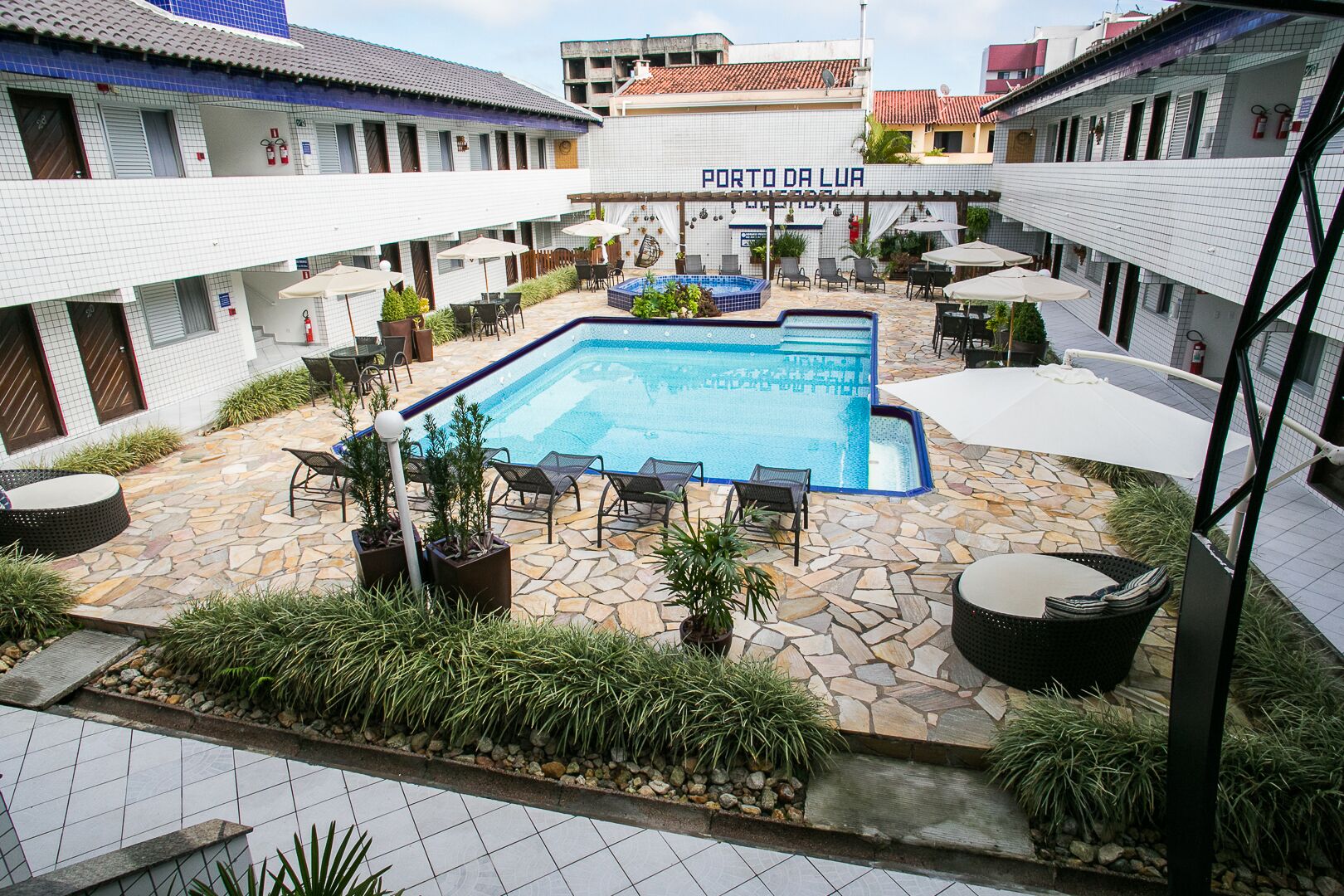Um pátio com piscina, área de estar ao ar livre e uma placa com a inscrição 'PORTO DA LUA'.