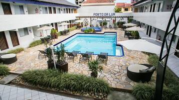 Um pátio com piscina, área de estar ao ar livre e uma placa com a inscrição 'PORTO DA LUA'.