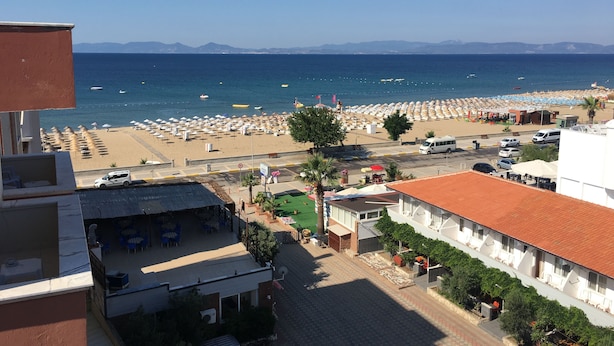A coastal view with a beach, umbrellas, and a clear sky.