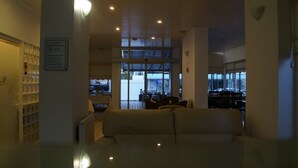 A hotel lobby with a sofa, a reception desk, and a view of the street through large windows.