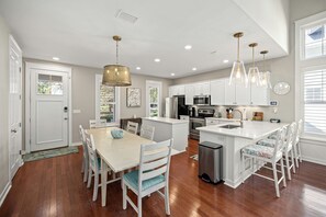 Une cuisine moderne avec des meubles blancs, des appareils en acier inoxydable et un îlot central doté de tabourets de bar.