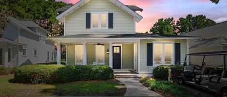 A two-story house with a front porch, a garage, and a golf cart parked outside.