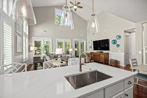 A spacious kitchen with a large island, pendant lighting, and a ceiling fan.