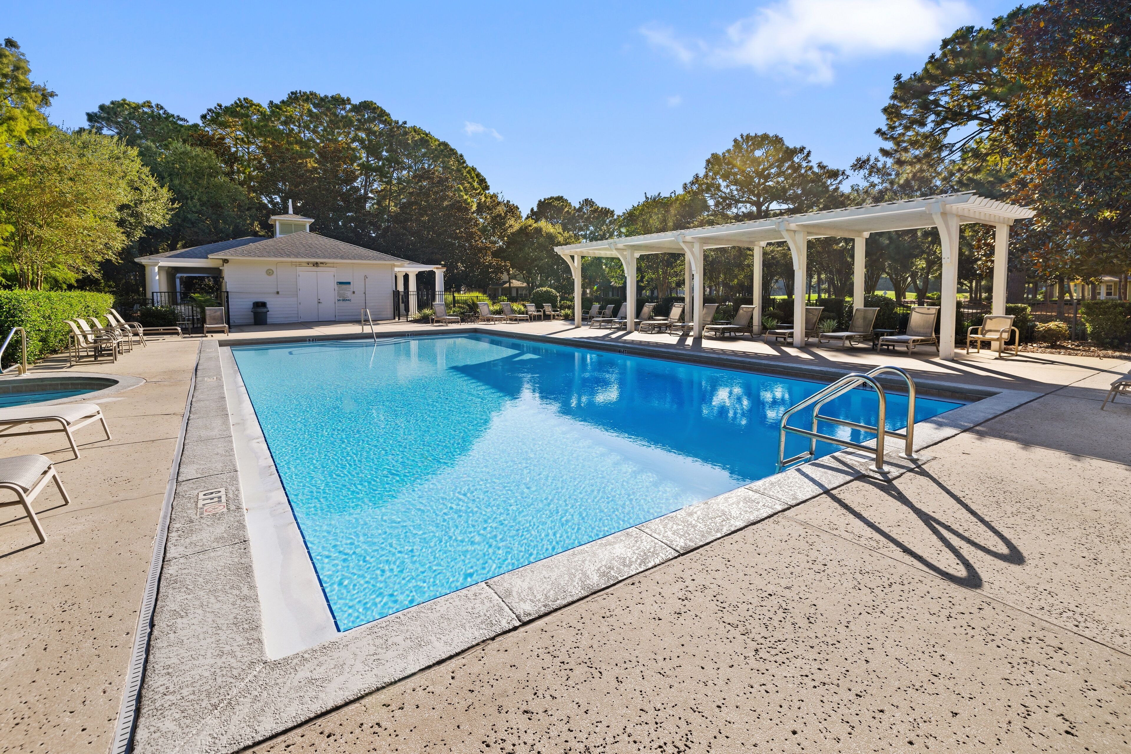 A swimming pool with lounge chairs and a covered seating area.