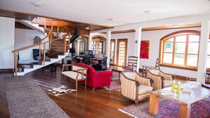 Un salón amplio con una escalera de madera, un escritorio para ordenador y un mobiliario cómodo.