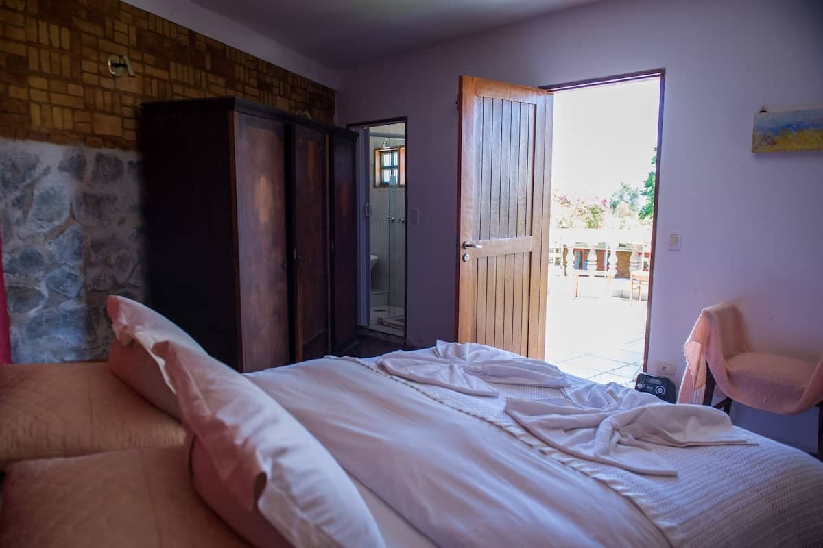 Ein Schlafzimmer mit Bett, Kleiderschrank und einer Tür zu einem Außenbereich.