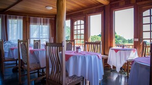 Un restaurante con interiores de madera, ventanas amplias y mesas dispuestas para comer.