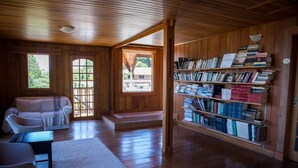Una habitación acogedora con paredes de madera, una estantería, un sofá y una ventana.