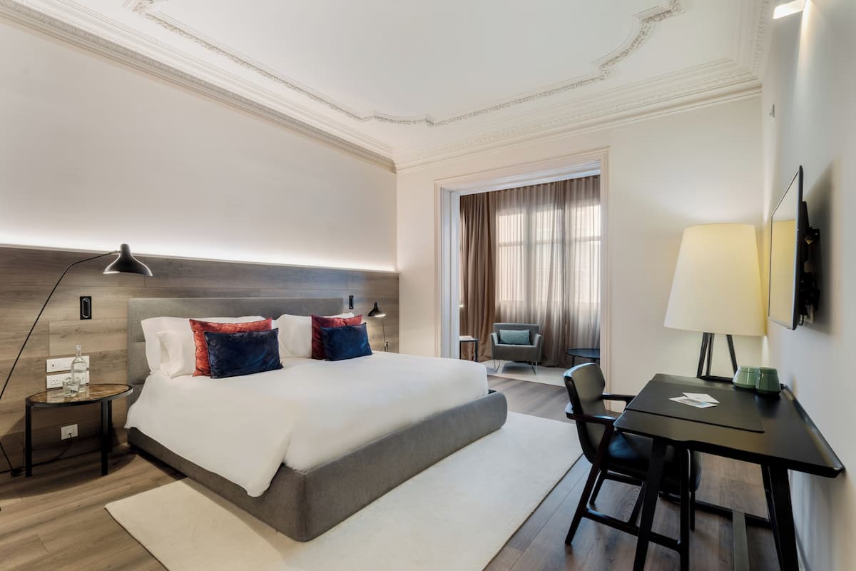 Hotelkamer met een groot bed, een bureau, een stoel, een televisie en een raam met gordijnen.