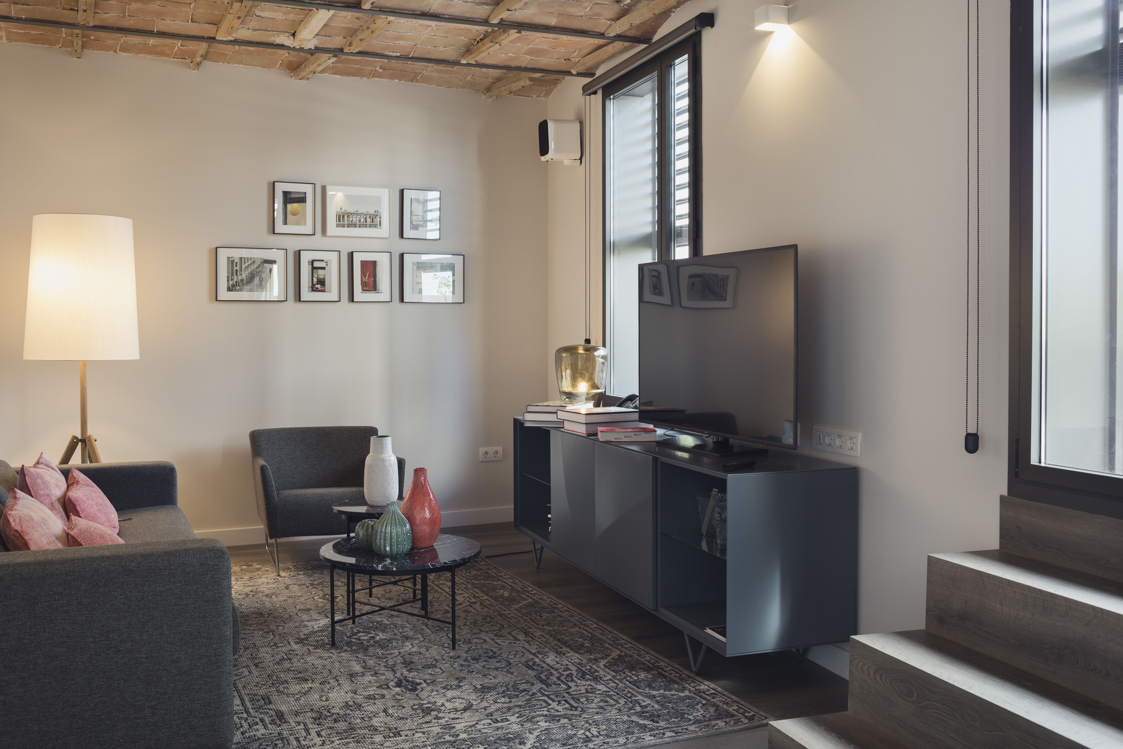 A modern living room with a sofa, a coffee table, a lamp, a TV, and a bookshelf.