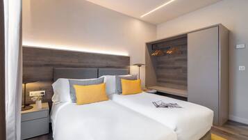 Una habitación de hotel moderna con una cama grande, mesitas de noche, un armario y un vestidor empotrado con espacio para colgar ropa.