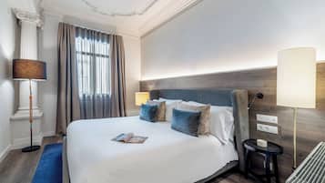 A hotel room with a large bed, a bedside table, a lamp, and a window with curtains.