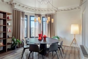 Un comedor moderno con una mesa redonda, sillas negras, una estantería y una planta en maceta.