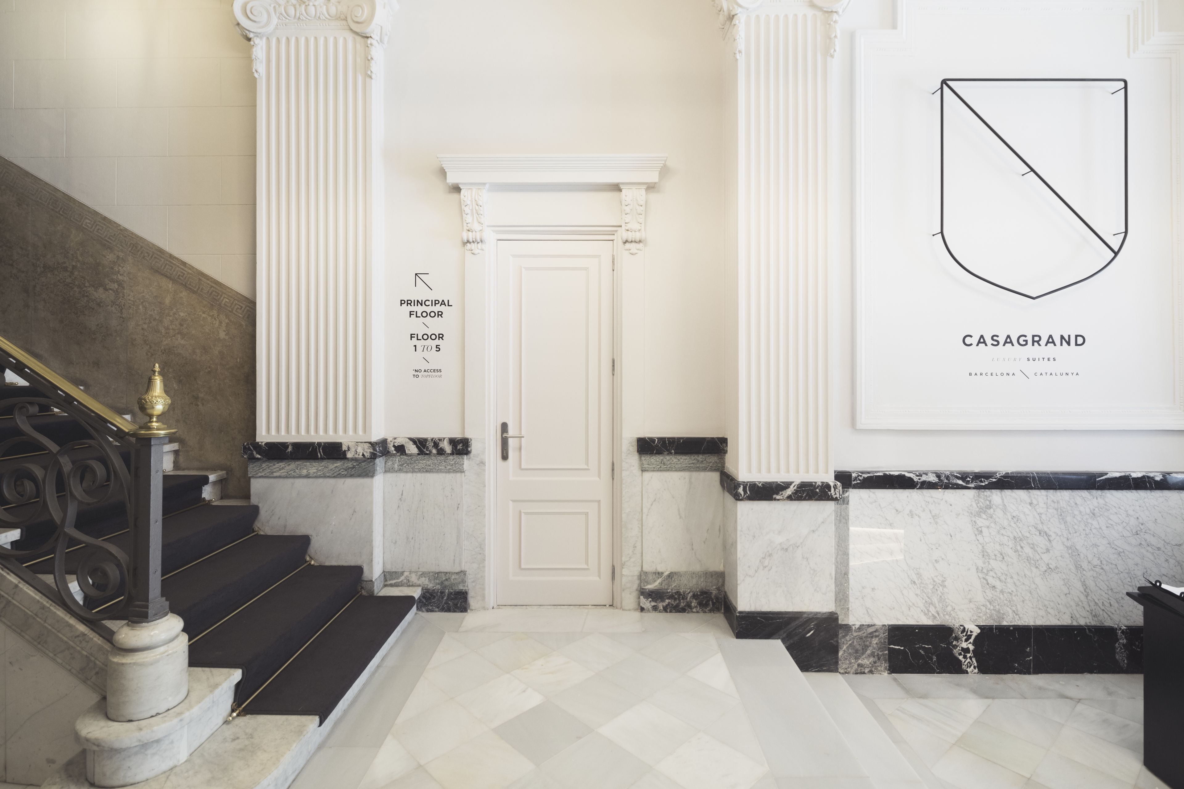 A grand staircase leading to a door labeled "Principal Floor 1/5" with a sign indicating "No Access." A large framed logo of "CASAGRAND" is displayed on the wall.