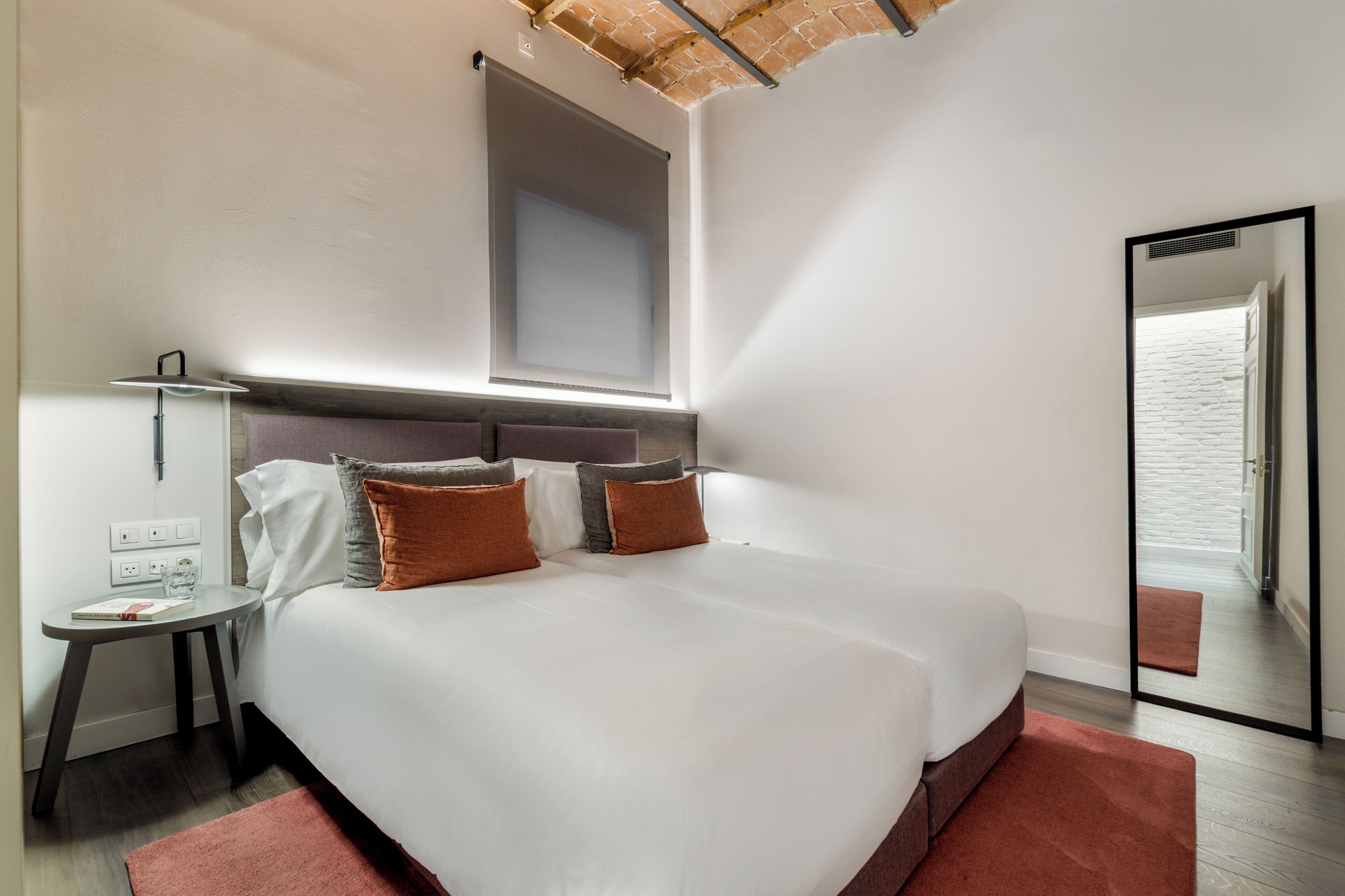 Et moderne hotelværelse med en stor seng, et natbord, en lampe og udsigt ud af vinduet.