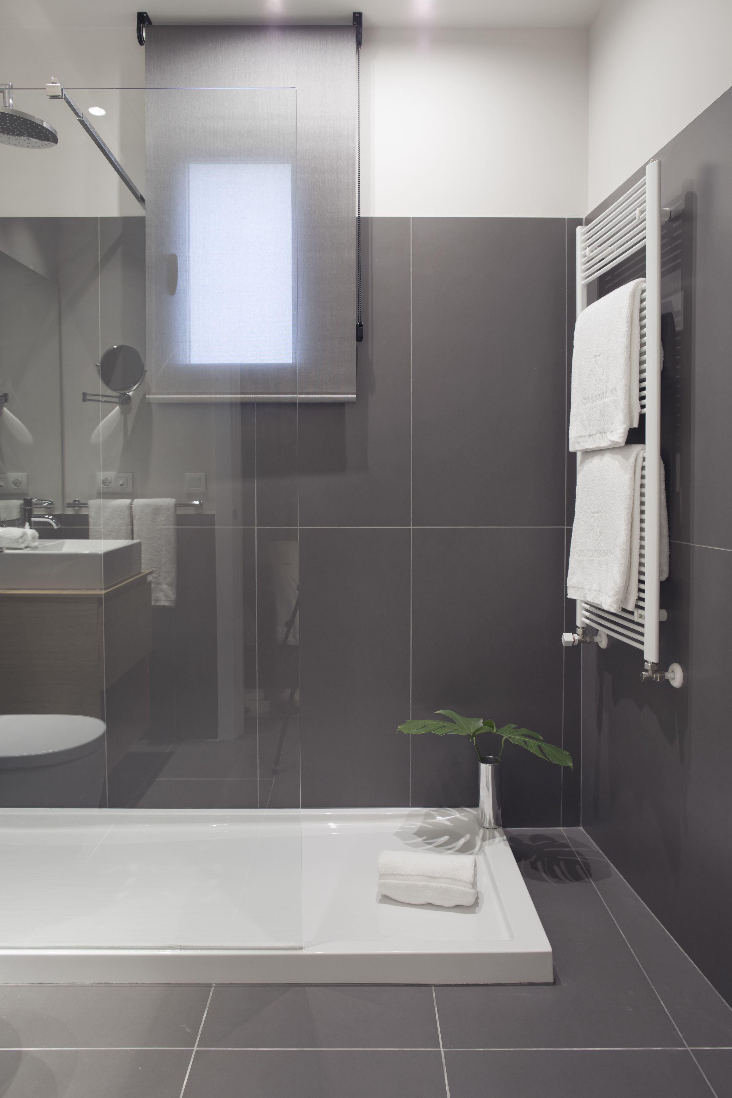 A modern bathroom with a glass shower enclosure, a white bathtub, a sink, and a towel rack.