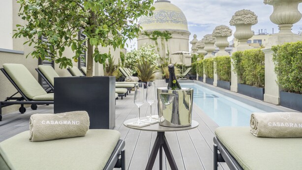 Un espace aménagé au bord de la piscine, avec des chaises longues, un seau à champagne et une bouteille.