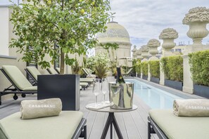 Un espace aménagé au bord de la piscine, avec des chaises longues, un seau à champagne et une bouteille.