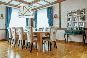 Ein Esszimmer mit Holztisch und -stühlen, einer Chandelier und einer Spiegelwand.