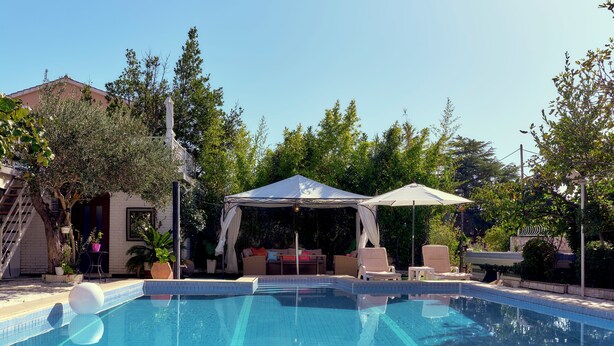 Piscina com área de estar coberta e espreguiçadeiras.