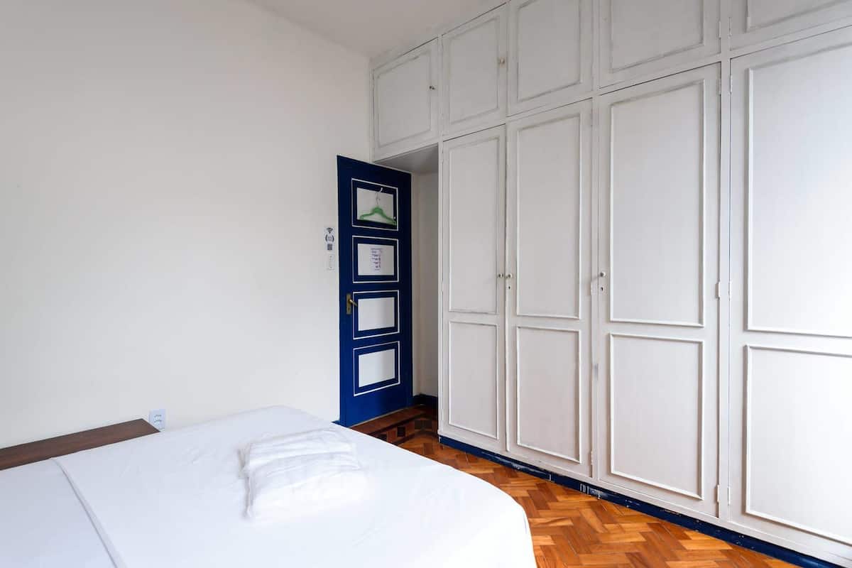 Un dormitorio con cama, armario y puerta con un cartel.