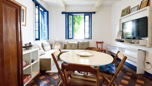 A cozy living room with a round table, a sofa, and a television. - Farfalla Guest House (Rio de Janeiro)
