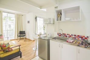 A compact kitchen with a microwave, sink, and a small dining area with a chair and table.