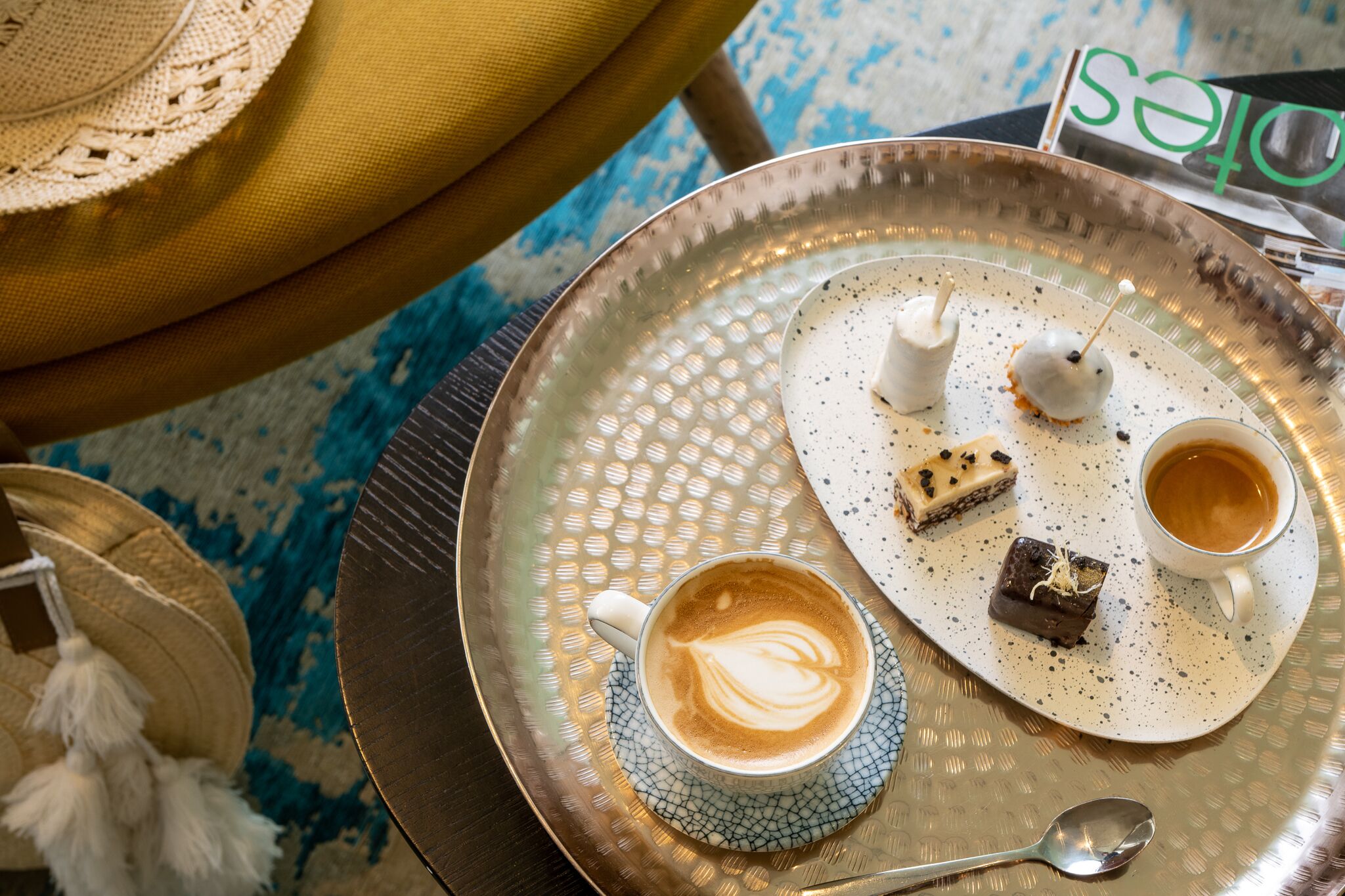 A tray with a cup of coffee, two desserts, and a spoon.