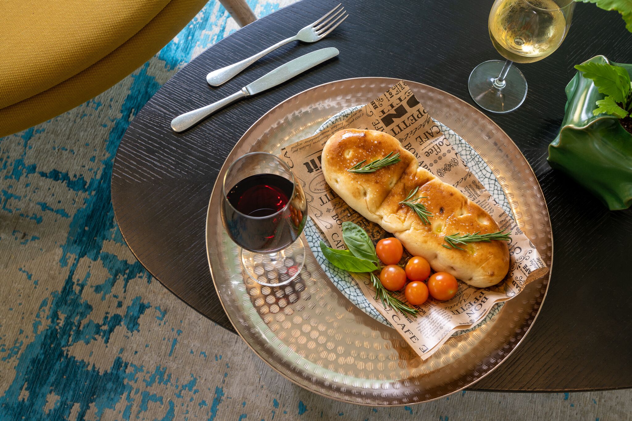 A dining table with a plate of food, a glass of red wine, and a glass of white wine.