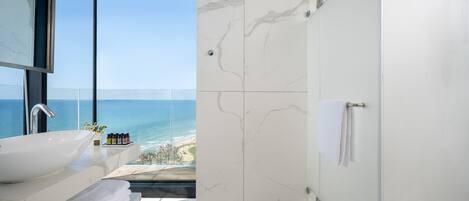 Un baño moderno con un lavabo blanco grande, un espejo y una zona de ducha.