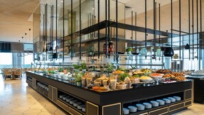 A modern buffet setup with various food items and a glass display case. - Vert Lagoon Netanya By AFI Hotels (Netanya)
