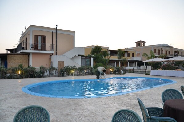 A swimming pool with lounge chairs, a building with a balcony, and a fountain. - Eolian Residence (Lipari)