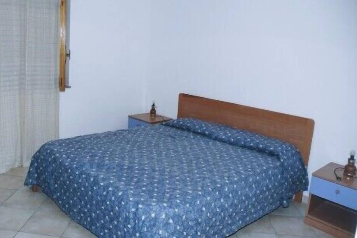 A bedroom with a bed, a nightstand, and a wooden headboard.