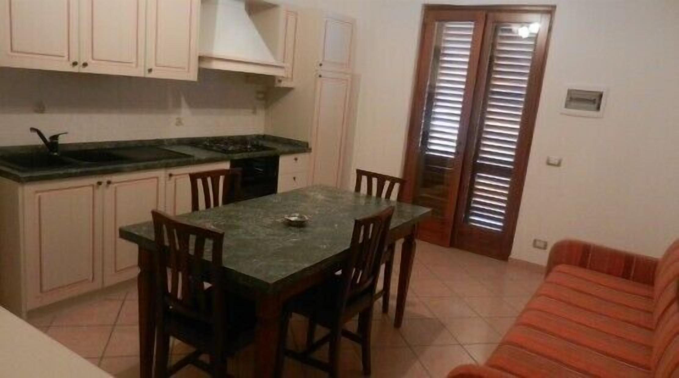 A compact kitchen with a dining table and chairs, a built-in oven, and a sink.