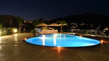 Una piscina al aire libre de temporada, sombrillas