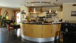 A bar area with a curved counter, shelves with bottles, and hanging lights. - Eolian Residence (Lipari)