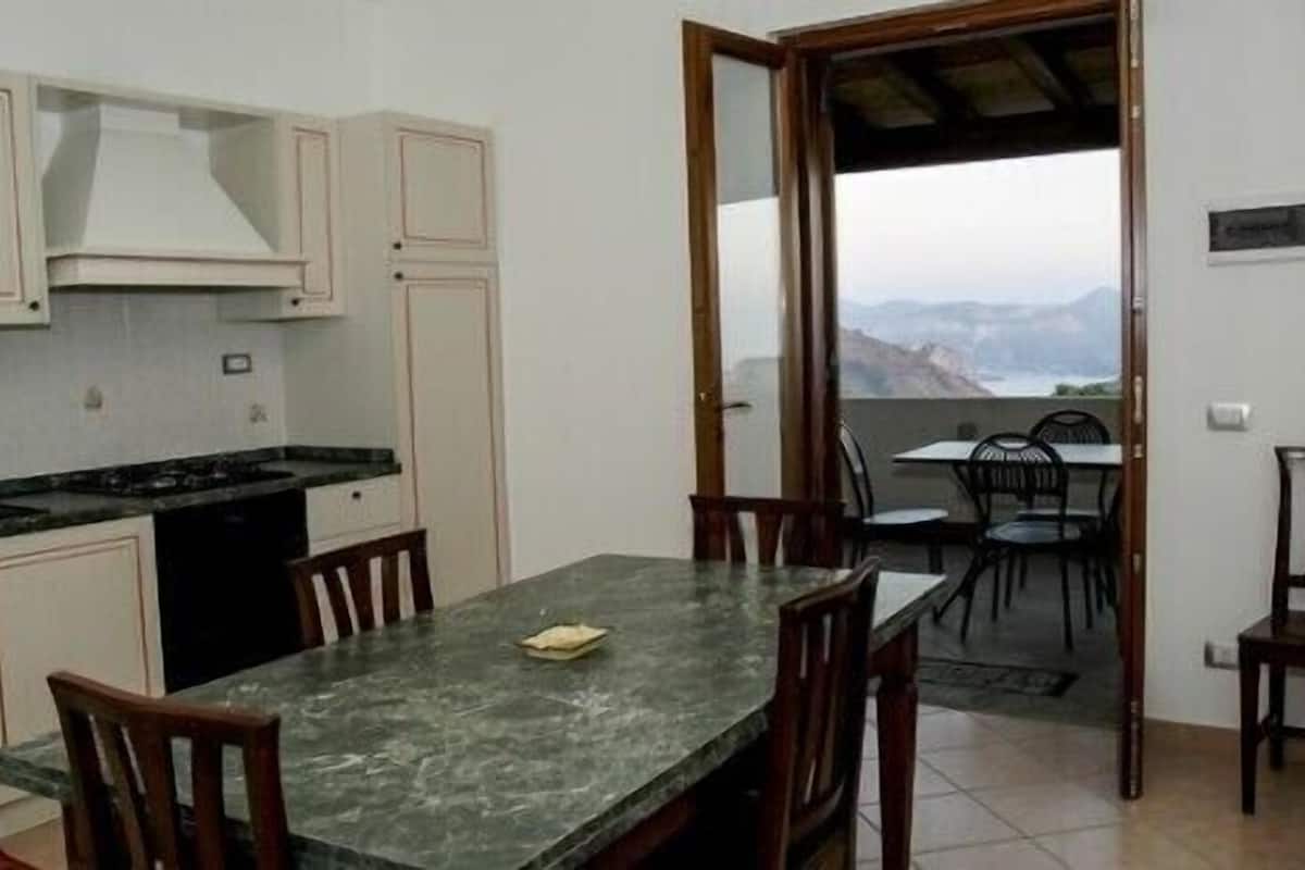 A kitchen with white cabinets, a black stove, and a dining area with a table and chairs.