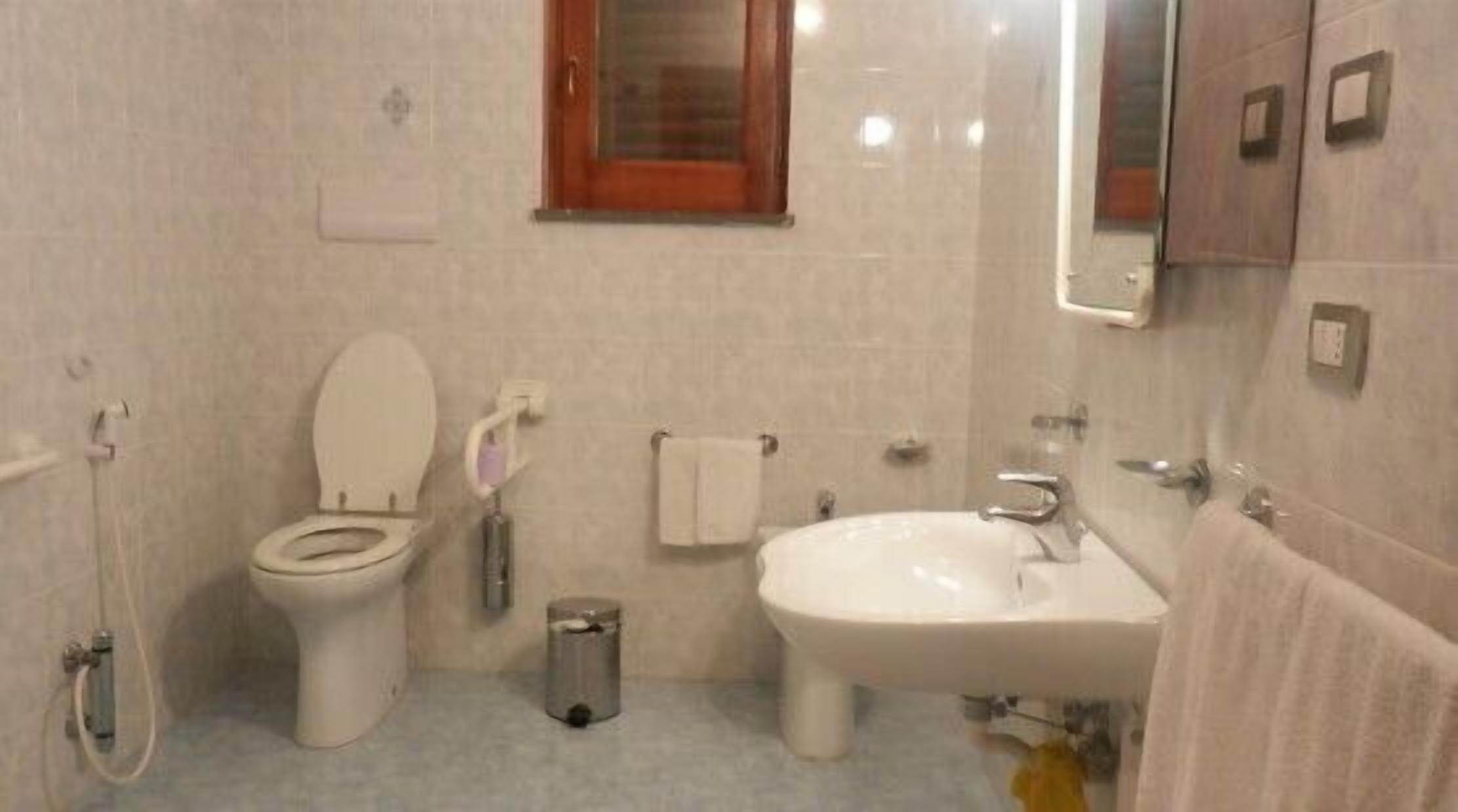Een badkamer met toilet, bidet, wastafel en spiegel.
