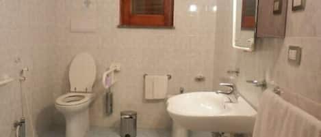 Un baño con inodoro, bidé, lavabo y espejo.