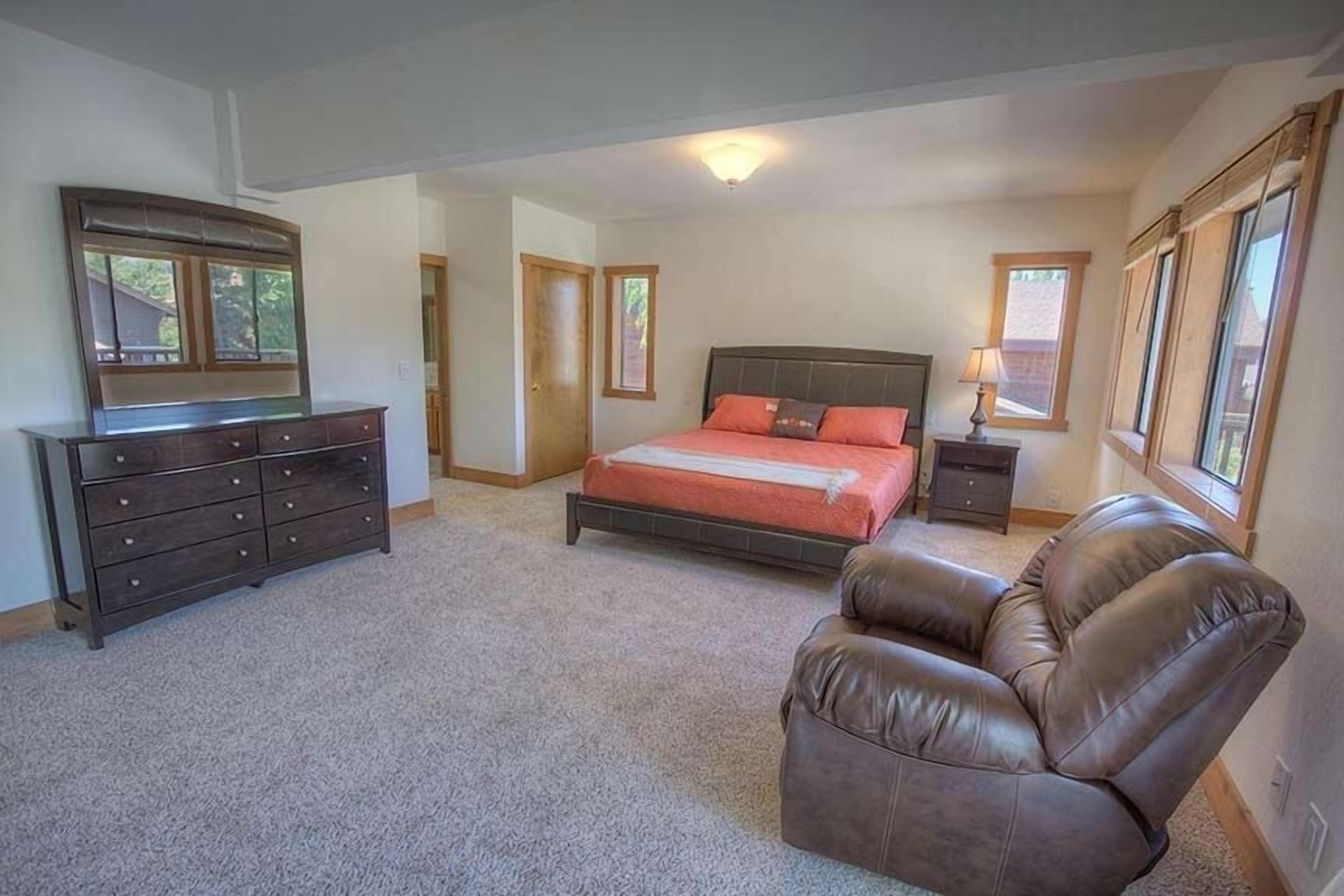 A bedroom with a bed, dresser, chair, and a window.
