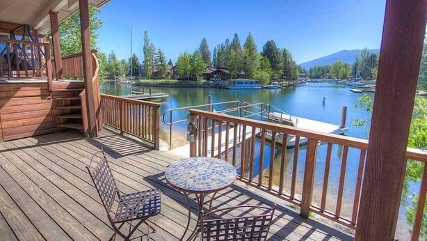 A wooden deck with a view of a lake, a small table, and two chairs. - 569 Lucerne 4 Bedroom Home by RedAwning (South Lake Tahoe)